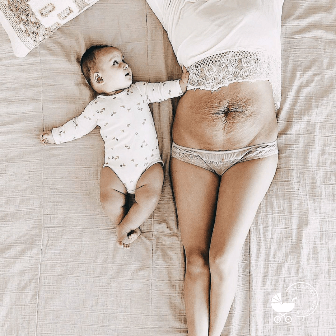 Mother with baby laying on bed. Mother showing stretch marks and c-section scar on her stomach..